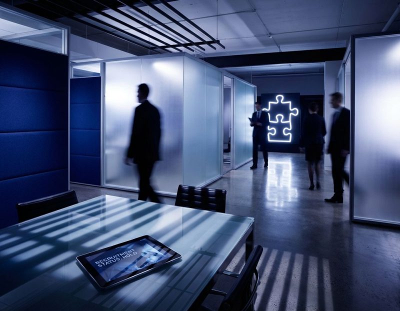 moderne glazen vergadertafel in kantooromgeving met zakelijke professionals in gang met glazen wanden op achtergrond