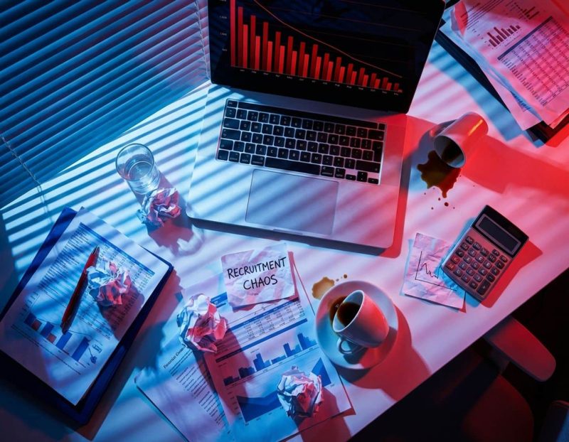 modern kantoorbureau van bovenaf met financiële documenten, laptop met dalende grafieken en omgevallen koffiekop
