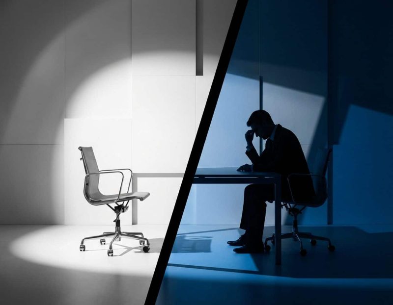 lege moderne bureaustoel in wit licht naast bezorgde professionele silhouet in blauwe schaduwen, dramatische kantooromgeving