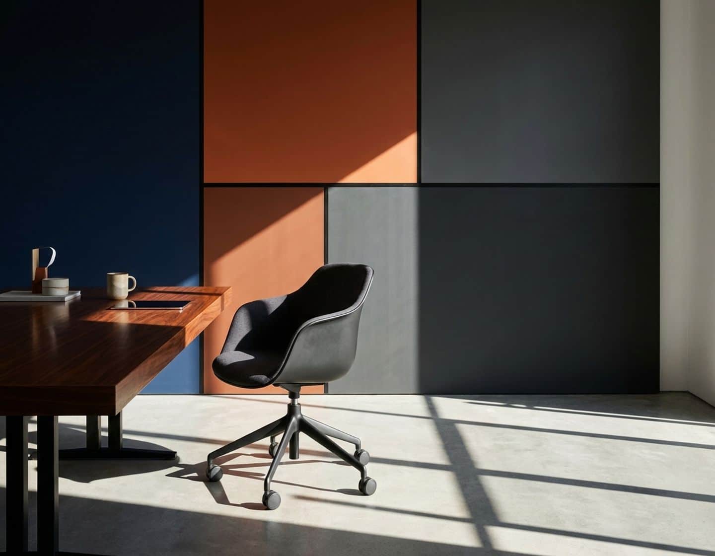 lege moderne bureaustoel aan strakke desk met dramatische belichting en blauw-oranje kleurblokken achtergrond