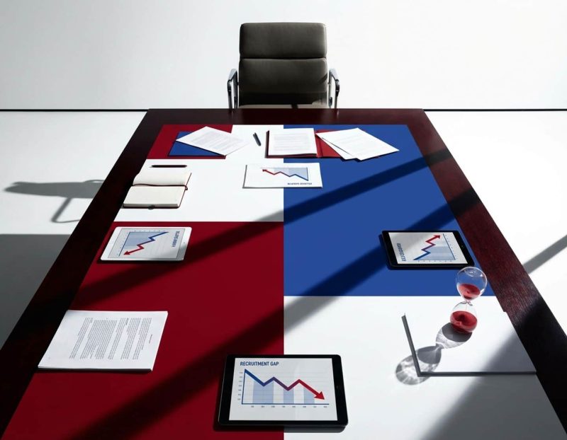 lege stoel aan vergadertafel met zakelijke documenten, dalende groeicurves en zandloper die vertragingen symboliseert